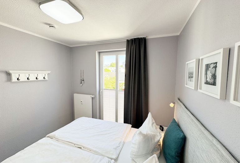 Schlafzimmer mit Boxspringbett, Nachttischablagen sowie Verdunkelungsvorhang