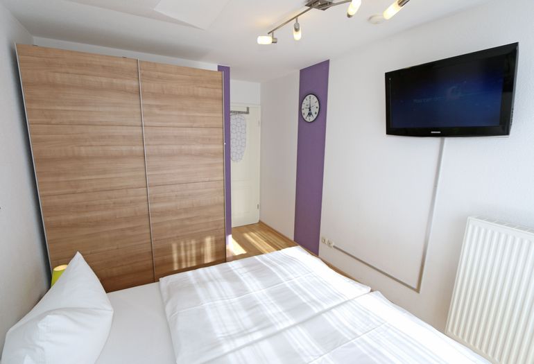 Schlafzimmer mit Doppelbett und TV