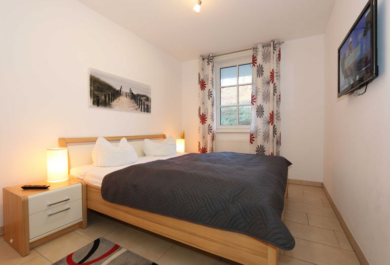 Schlafzimmer mit Doppelbett und TV