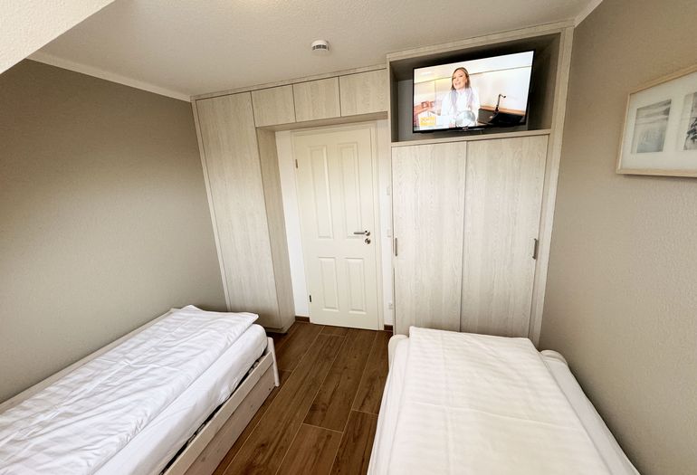 kleines Schlafzimmer mit TV und Einbaukleiderschrank