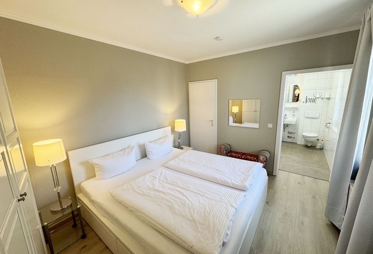 Schlafzimmer mit Doppelbett und Blick ins Badezimmer