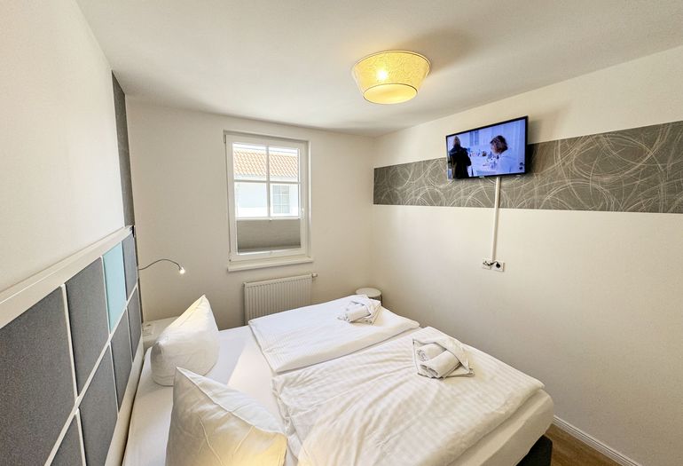 modernes Schlafzimmer mit TV und Verdunklungsmöglichkeiten