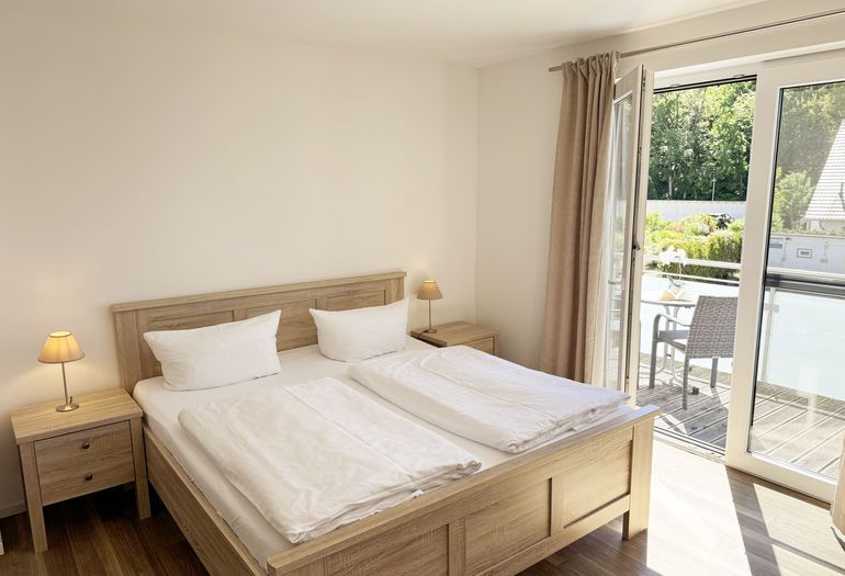 Schlafzimmer mit Doppelbett und Zugang zum Balkon