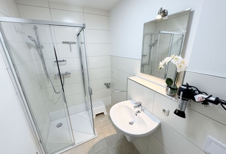 Badezimmer mit ebenerdiger Dusche und Waschbecken