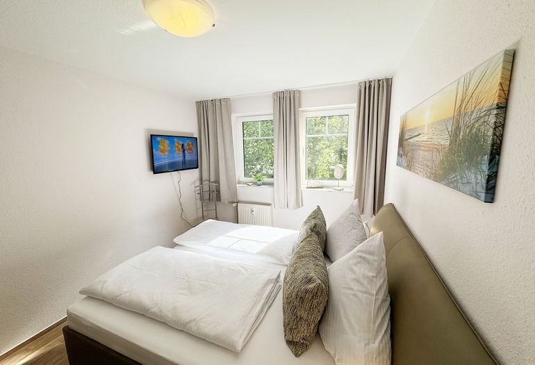 Schlafzimmer mit Doppelbett und TV