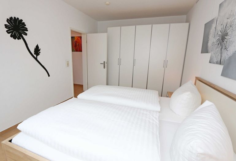 helles Schlafzimmer mit Doppelbett und Kleiderschrank