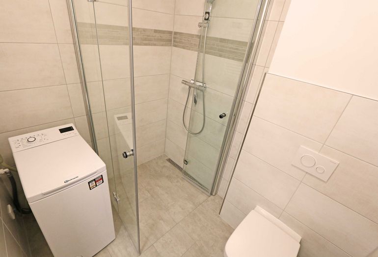 Badezimmer mit Dusche und Waschmaschine Badezimmer mit Dusche und Waschmaschine