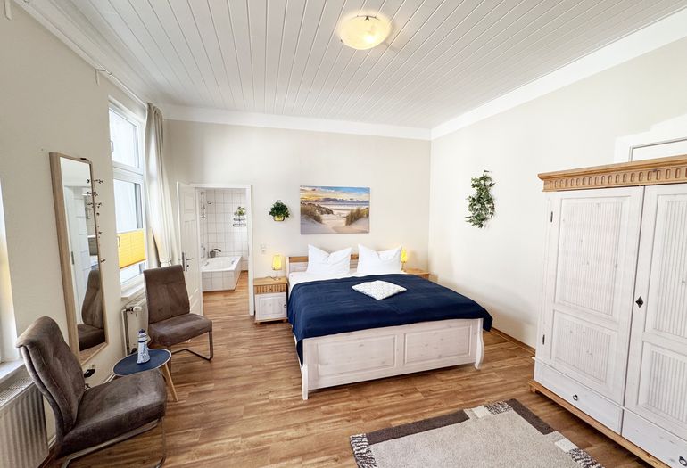 Schlafzimmer mit Doppelbett und Blick ins Badezimmer