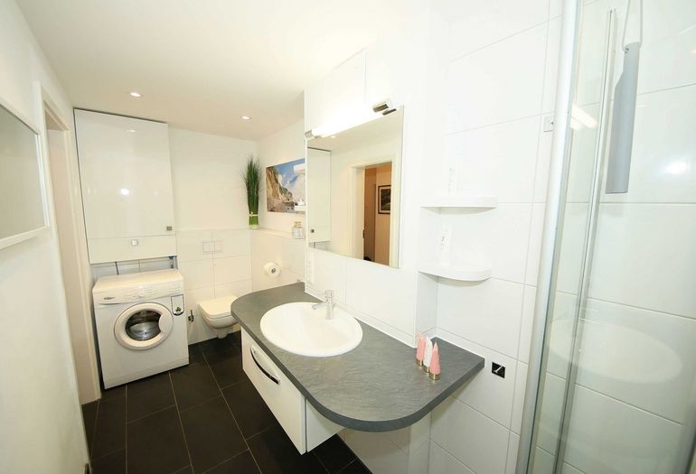 Badezimmer mit Waschmaschine, Waschbecken und WC