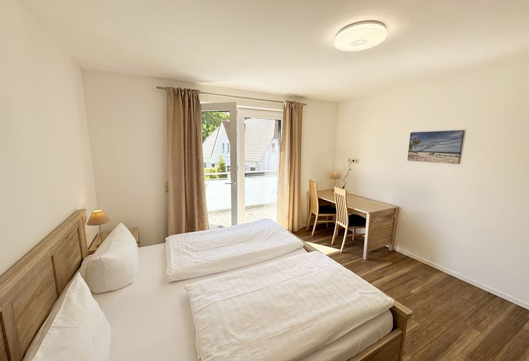 Schlafzimmer mit Doppelbett und Schreibtisch