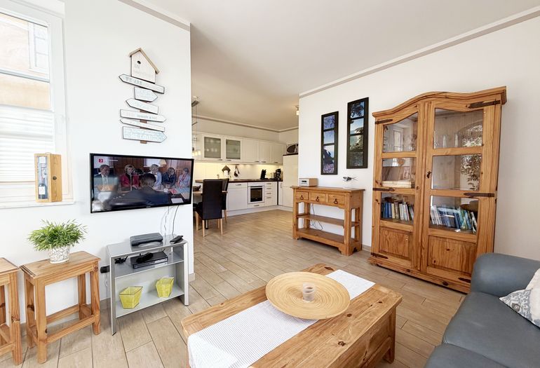 gemütlicher Wohnbereich mit Ecksofa, Glasvitrine und Smart-TV gemütlicher Wohnbereich mit Ecksofa, Glasvitrine und Smart-TV