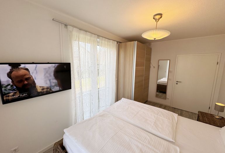 Schlafzimmer mit Doppelbett und Fernseher