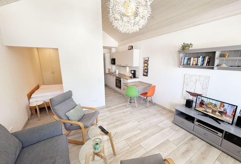 gemütliches Wohnzimmer mit Couch und blick ins Schlafzimmer