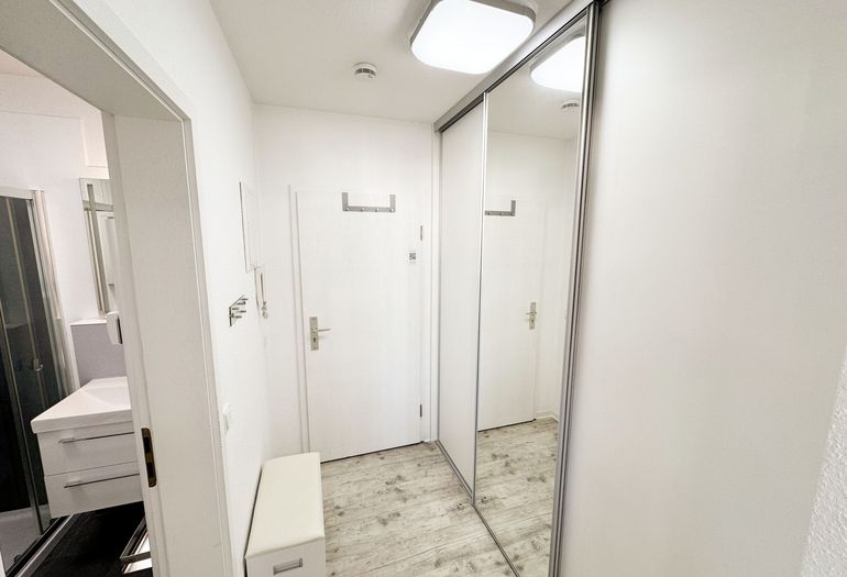 freundlicher Eingangsbereich mit großem Spiegel und Schuhablage mit Sitzbank