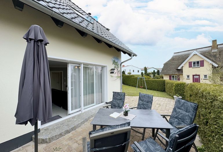 bestuhlte Terrasse mit Blick auf das Grundstück mit Schaukel