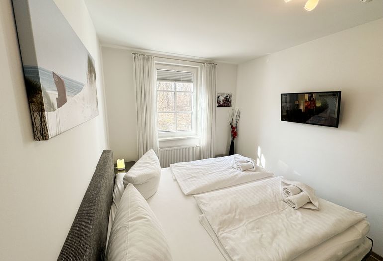 Wohnung Ostseesilber - Blick über das Doppelbett zum TV Wohnung Ostseesilber - Blick über das Doppelbett zum TV
