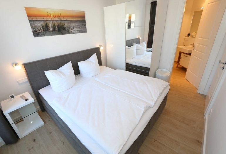 erstes Schlafzimmer mit Kleiderschrank und kleinem Bad