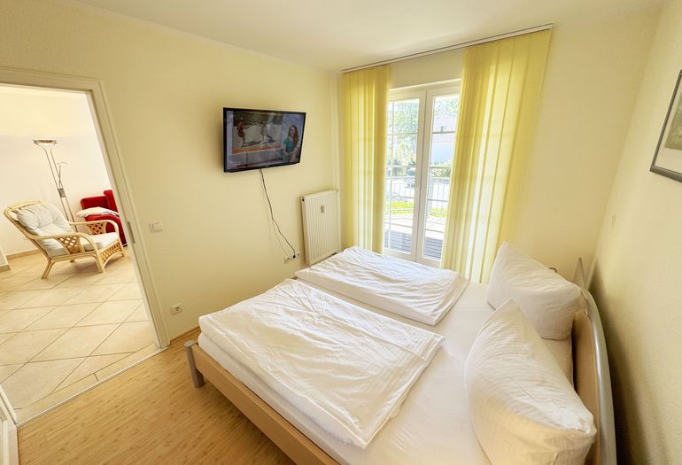 Schlafzimmer mit Doppelbett und TV