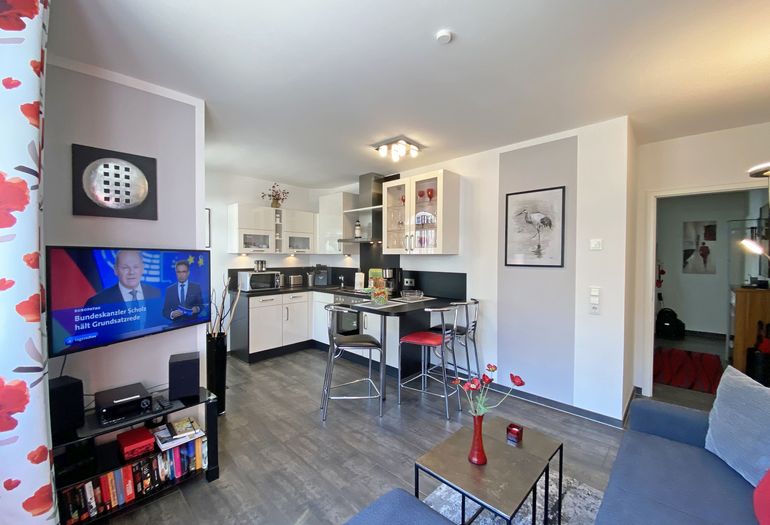 Wohnzimmer mit TV und Blick zur Küchenzeile