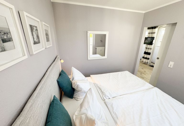 Schlafzimmer mit Boxspringbett, komfortabler Topper, Nachttischablagen sowie Verdunkelungsvorhang