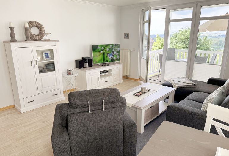 Wohnzimmer mit gemütlicher Couch, Couchtisch, Sessel sowie Smart-TV Wohnzimmer mit gemütlicher Couch, Couchtisch, Sessel sowie Smart-TV