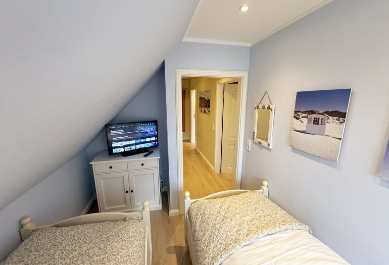 kleines Schlafzimmer mit TV und Blick in den oberen Flurbereich